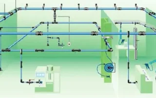 Rede de distribuição de ar comprimido industrial com tubulações aéreas interligadas, múltiplos pontos de consumo, derivações, válvulas e conexões distribuídas pelo ambiente fabril para alimentar máquinas e equipamentos pneumáticos.