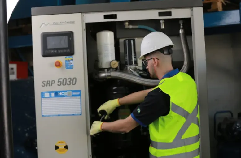 Técnico realizando manutenção em compressor de parafuso industrial, verificando componentes internos e sistema de ar comprimido.