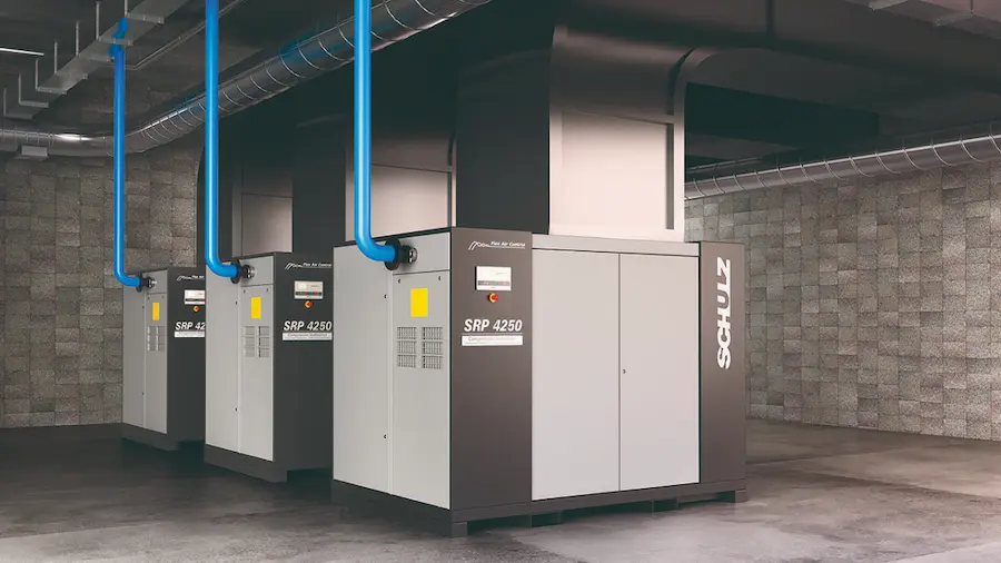 Três grandes compressores industriais Schulz alinhados em uma sala de máquinas com tubulações verticais azuis.